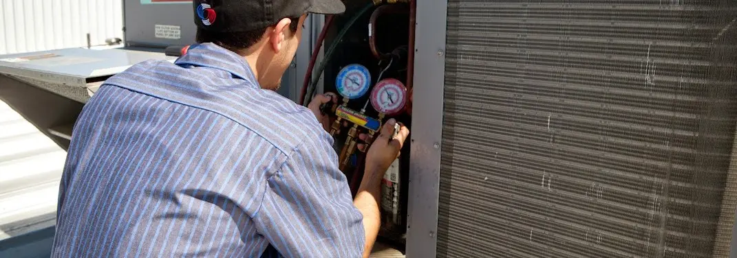 HVAC technician servicing a condenser unit in South Run